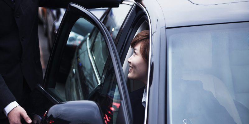 Businessman opening car door for businesswoman during the day in Beijing Businessman opening car door for businesswoman during the day in Beijing